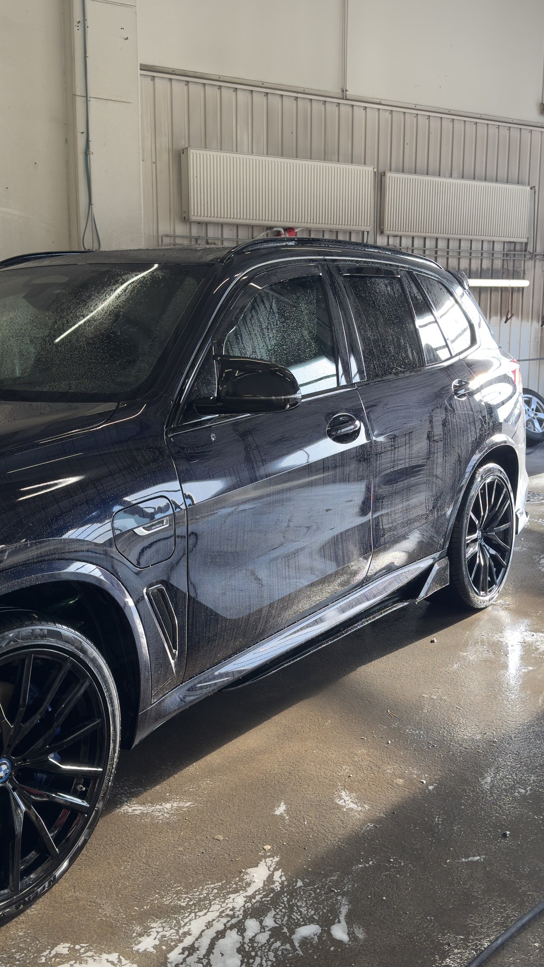 Musta BMW X5 külg hooldusaine pealekandmise ajal, pind on märg