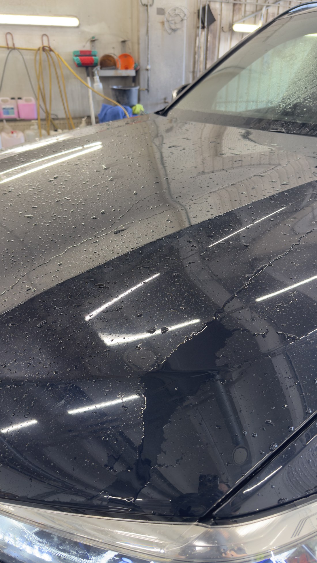 Musta BMW X5 kapott loputuse ajal, vesi on tõmbunud tilkadeks ja osa pinnast on juba kuiv
