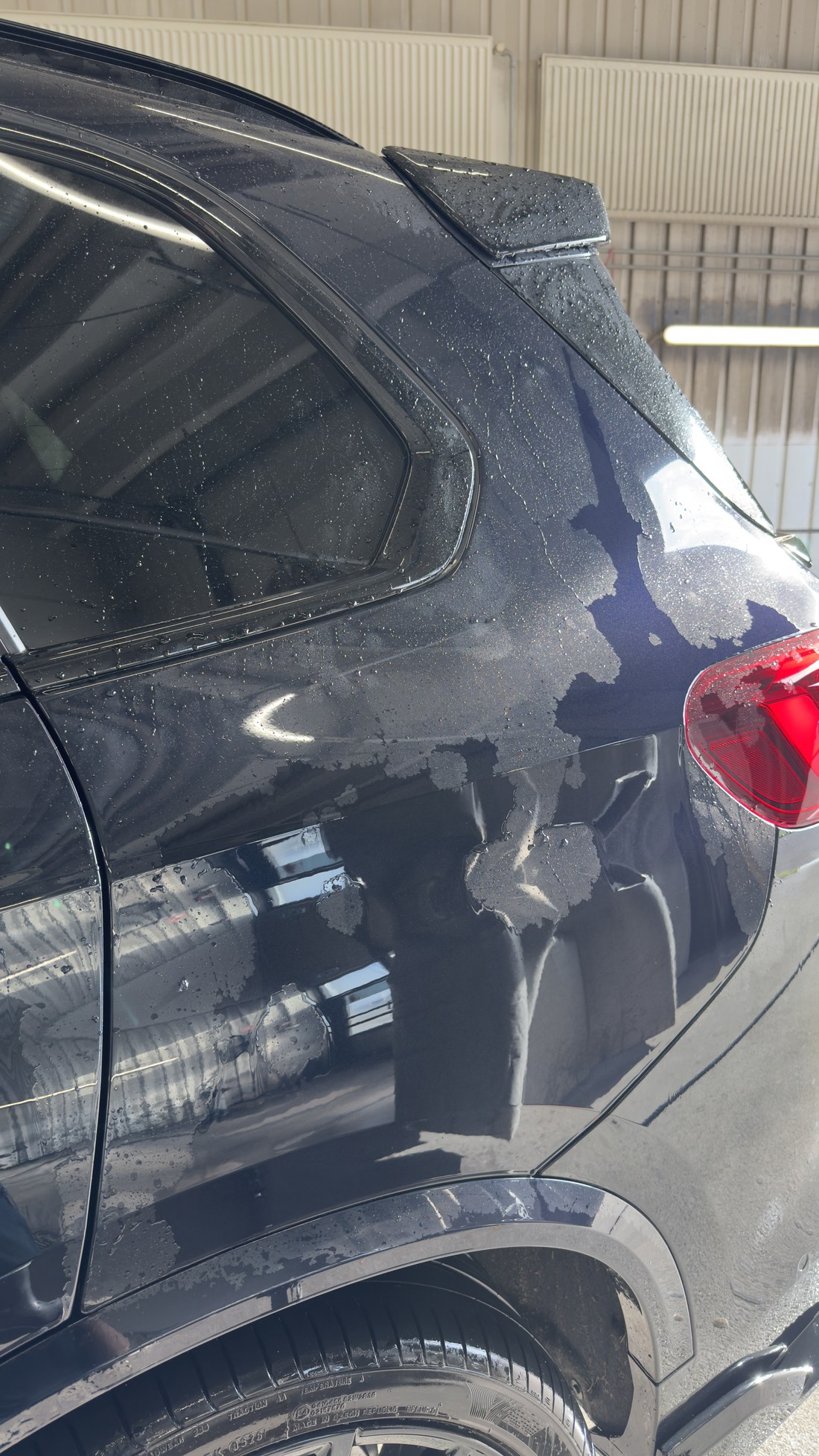 Musta BMW X5 tagatiib ja tagaluuk loputuse ajal, vesi on jooksnud maha ja jätnud kuivad laigud