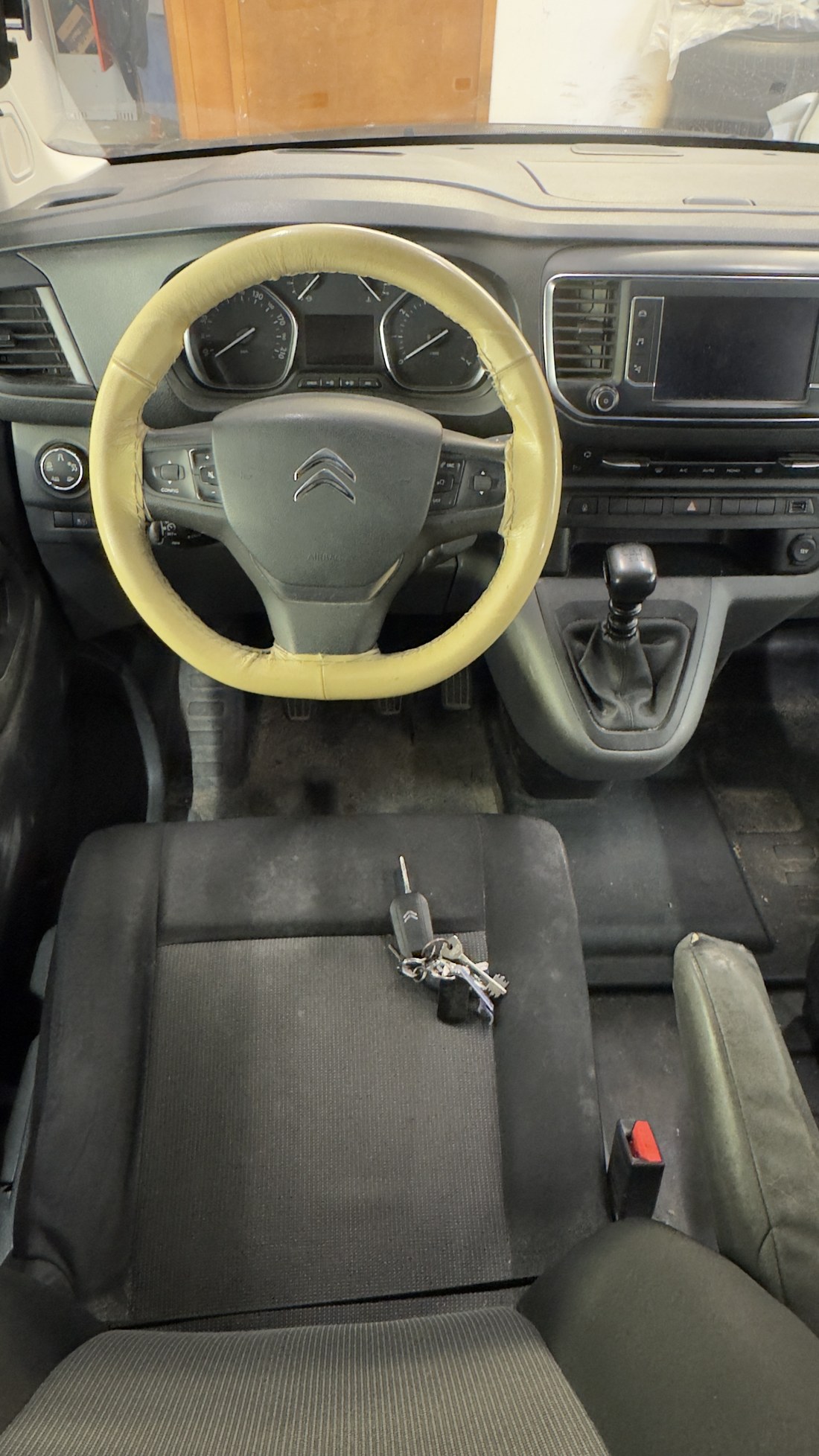 Citroën Jumpy juhiiste ja pedaalide ala ülevalt enne tööd, istmel võtmed ja põrandal mustus